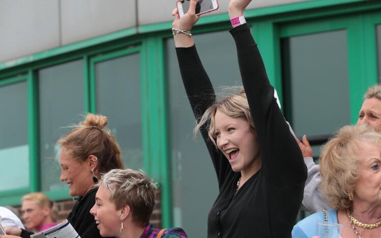 A race goer celebrating her win at Brighton Races with her arms in the air